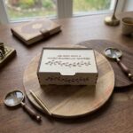 Personalizējama koka kastīte ar gravētu uzrakstu un dekoratīvu zaru ornamentu uz vāka, izmērs 20 × 15 × 5 cm.