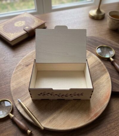 Personalizējama koka kastīte ar gravētu uzrakstu un dekoratīvu zaru ornamentu uz vāka, izmērs 20 × 15 × 5 cm.